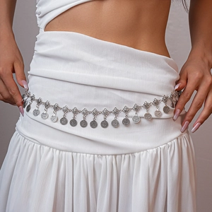 Detail of vintage silver waist chain with engraved coin pendants on a white dress