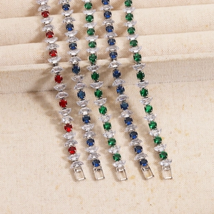 Five colored zircon bracelets in red, blue, and green on a beige jewelry display tray