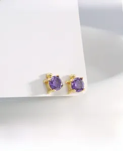 Macro view of gold turtle studs featuring purple faceted gemstones on white display