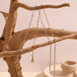Minimalist 14K gold and silver plated heart chain anklets hanging on a wooden branch