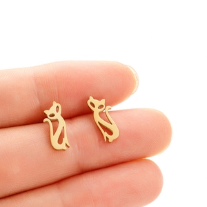 Boucles d'oreilles puces chat minimalistes en acier inoxydable doré sur le doigt
