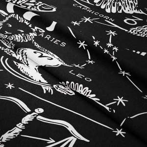 Detail of bohemian tapestry featuring white zodiac signs printed on black fabric background