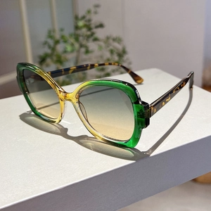 Detail of square gradient frame sunglasses with tortoiseshell temples on grey surface