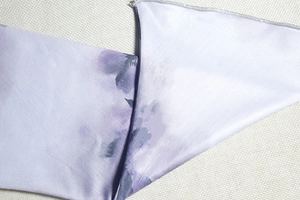 Détail du tissu tie-dye violet à fleurs avec surjet fin et texture lisse