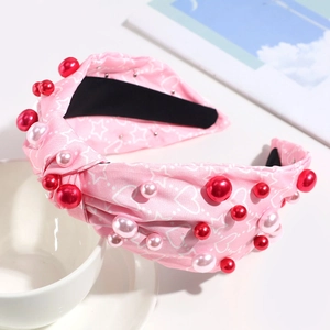 Detailed view of pink knotted headband with white hearts, stars and faux pearl accents
