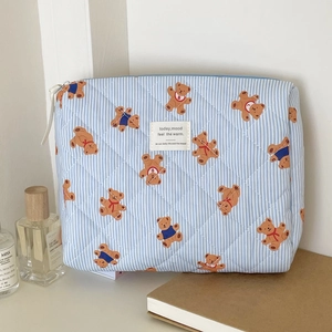 Macro detail of quilted teddy bear pattern on blue striped cotton makeup storage bag