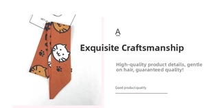 Detail of orange hair ribbon with black cat faces and paw prints on smooth fabric