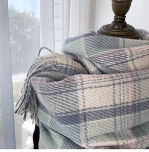 Detailed view of soft cashmere-like scarf texture with pastel plaid and tassel trim