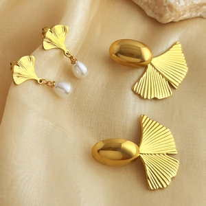 Ginkgo leaf stud earrings with white pearl and golden fan dangle on beige silk