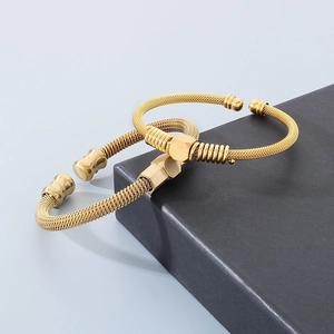 Close-up of golden cable wire open bracelets with hexagonal center charms in pair