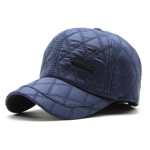 Close-up of quilted diamond texture and black metal logo on navy blue winter baseball cap
