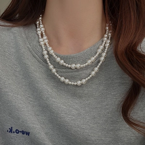 Élégant collier de perles dégradé à double rangée présenté sur un mannequin en pull gris
