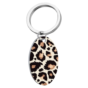 Macro view of oval leopard print keychain pendant with polished metal ring on white back