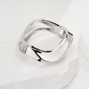 Close-up of a silver twisted geometric metal bangle on a white stone pedestal