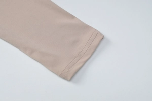 Détail de la couture double sur le poignet d'une robe beige à manches longues en maille