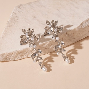 Detailed view of floral pearl earrings with leaf vine drops and silver metallic finish