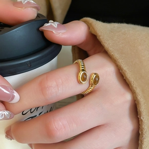 Detailed view of an adjustable gold textured ring with oval brown gemstones on a hand