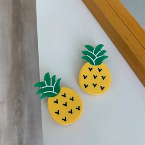 Detail shot of two pineapple-shaped acetate hair clips with yellow and green color tones
