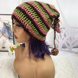 Detail of pink and green striped crochet cat ear hat with decorative pom pom tassels