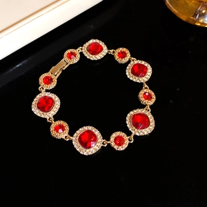 Vintage style gold bracelet featuring deep red crystals and sparkling white rhinestones