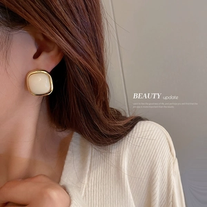 French minimalist geometric square cream pearl earrings with gold metal frame on model