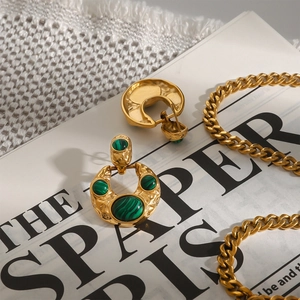 Close-up of vintage gold titanium steel earrings with green malachite stone insets