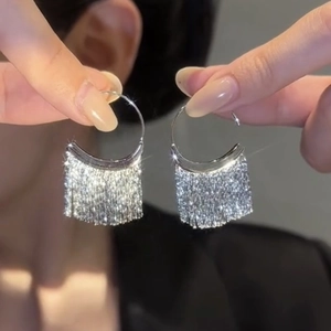 Vue détaillée de boucles d'oreilles cœur argentées avec cristaux tenues par la main