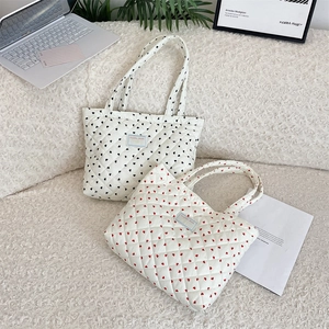 Close-up of quilted heart pattern tote bags with logo detail on soft texture