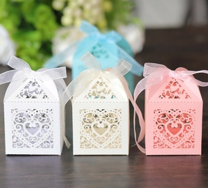 Detailed view of laser-cut heart candy boxes in pink, white and blue colors for weddings