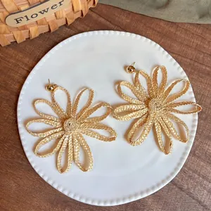 Detail of handcrafted raffia sunflower earrings on a white ceramic plate
