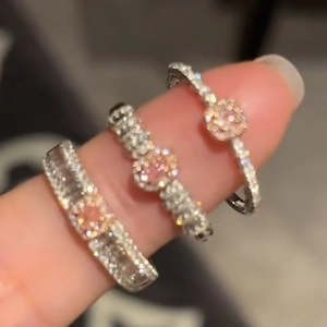 Close-up of three silver geometric zircon rings with pink and clear stones on finger
