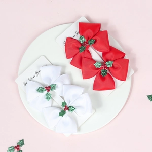 Detail view of Christmas bow hair clips with holly leaf patterns in a white display dish