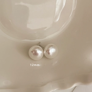 Close-up of 12mm high-luster white pearl stud earrings resting in a ceramic dish
