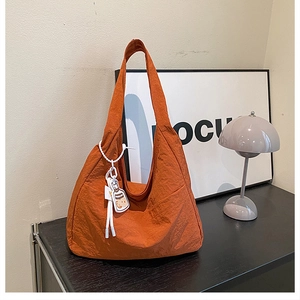 Detail of orange pleated nylon tote bag with white rope charm on a stylish shelf