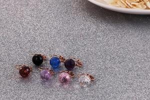 Macro shot of colorful faceted crystal earrings with rose gold clasps on a silver backdrop
