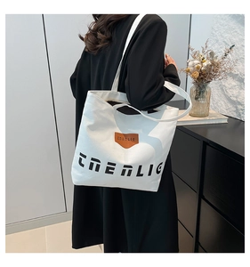 Detail showing the white canvas tote bag side profile with TRENLIG lettering and leather tag