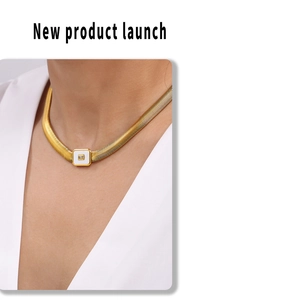 Detail view of a gold snake chain necklace with a white enamel rectangle zircon pendant