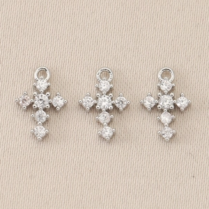 Detailed close-up of three silver cross pendants with shimmering inlaid clear gemstones
