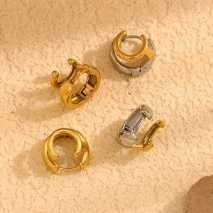 Vista dall'alto di orecchini circolari a strati in oro e argento su superficie beige