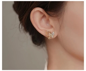 Close-up of golden butterfly earring with hollow wings and shimmering cubic zirconia stones