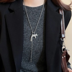 Detail of silver horse pendant necklace with chain tassels on a black blazer