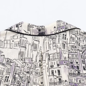Close-up of neckline detail on white shirt featuring artistic city architectural prints