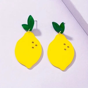 Macro view of vivid yellow acrylic lemon earrings with green leaf detail and smooth texture