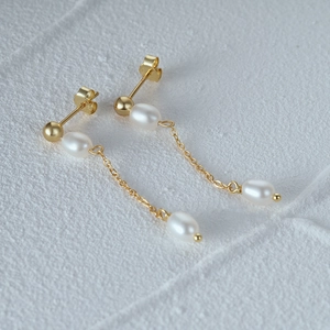 Macro detail of S925 silver gold-plated tassel earrings with white freshwater pearls