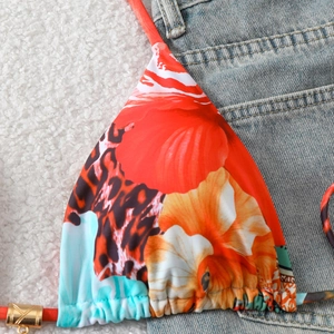 Detail of bikini top featuring leopard print, tropical florals and gold metal hardware