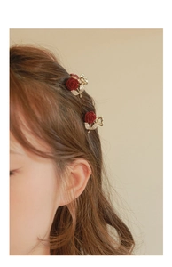 Detail view of two red flocked rose hair claws with rhinestones worn by a model