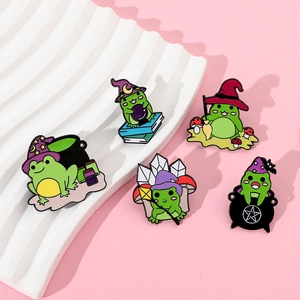 Set of five green witch frogs enamel pins displayed on a decorative white plate