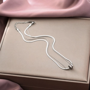 Detail of silver layered necklace with crystal ring pendant on beige jewelry box