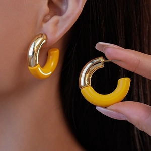 Macro view of gold and yellow acrylic C-shaped earrings showing elegant resin texture