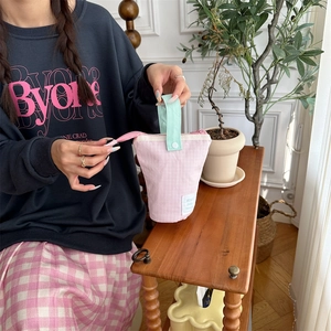 Pink checkered stationary pouch with green handle showing portable fabric texture details
